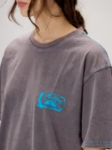 Remera oversize de corte cuadrado, color lila con efecto acid wash, cuello redondo y pequeño gráfico frontal en color rojo.