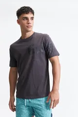 Remera de manga corta color beige claro, con escote redondo y fit regular. Presenta un estampado frontal con letras góticas en blanco.