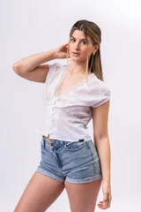 Blusa de lino liviano color blanco con textura plumeti, escote en V con detalle de encaje, botones frontales y mangas cortas.
