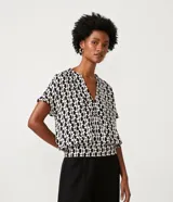 Blusa de viscosa con estampado geométrico en blanco y negro, escote de pico, manga corta y bajo elástico.
