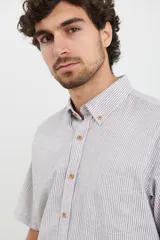 Camisa de manga corta a rayas verticales color celeste y blanco, con cuello abotonado y bolsillo en el pecho.