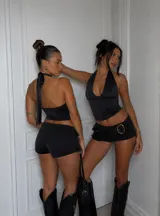 Minifalda tipo skort de tiro bajo en color negro, con diseño de bolsillos laterales tipo cargo y cinturón integrado con hebilla circular metálica.