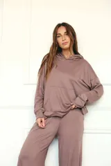 Canguro con capucha de manga larga, color marrón topo, de calce amplio y tejido suave. Presenta bolsillo canguro frontal y puños y ruedo ajustados.