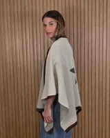 Ruana tejida de algodón en color marrón con detalles en off-white, destacando un diseño de estrella grande en la espalda y bordes en contraste.