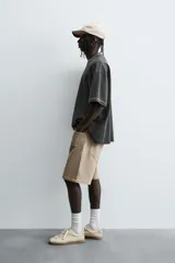 Camiseta color caqui de corte holgado, con cuello redondo y mangas cortas. Acabado con efecto lavado y ruedo irregular.