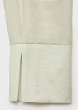 Camisa color verde agua, de corte cruzado con lazo en la cintura, cuello camisero, manga larga y bolsillo de parche en el pecho.