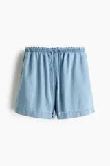 Short en denim liviano de mezcla de algodón y lyocell, modelo de tiro alto con cintura elástica de volado, cordón para ajustar fino y bolsillos laterales discretos. Corte holgado.