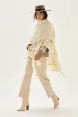 Ruana tejida en lana de cordero con diseño de sectores calados y terminación con flecos en los bordes.