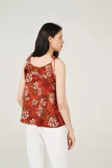 Musculosa color ladrillo con estampado de flores blancas y hojas verdes, breteles finos y escote redondo.