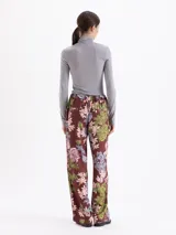 Pantalón de corte recto y holgado, con estampado floral y de fresas sobre fondo color marrón. Presenta cintura elástica y diseño fluido.