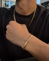 Conjunto de collar y pulsera dorados con eslabones de diseño intrincado.