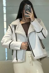 Campera tipo gamulán de color crema con interior y cuello de corderito sintético. Presenta cierre frontal cruzado, bolsillos laterales con cierre y detalles de costuras en contraste color marrón oscuro.