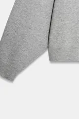 Sudadera gris de cuello redondo y manga larga, con puños y dobladillo acanalados.