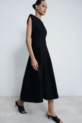 Vestido midi de Zara Woman Collection confeccionado en popelín de algodón. Presenta cuello redondo, manga corta y detalle de pliegues en la cintura que dan paso a una falda con caída evasé. Cierre posterior con abertura y botón.