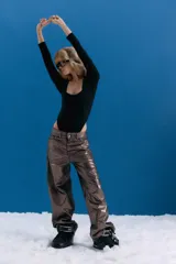 Pantalón de jean estilo oversize de tiro medio-bajo, confeccionado en denim 100% algodón. Presenta un acabado metalizado en tono peltre con efecto lavado violeta, logrando un brillo irregular y profundo. Incluye avíos metálicos personalizados y badana de PU en la parte posterior.