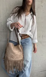Camisa de corte oversize, con diseño a rayas verticales marrón sobre fondo blanco, manga larga, cuello camisero y bolsillos frontales.