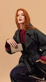 Billetera mediana de diseño bicolor en tonos beige y bordó, con cierre de solapa mediante presilla a presión. Presenta el logo de la marca grabado en la parte frontal y cuenta con compartimentos internos para tarjetas, billetes y monedas.