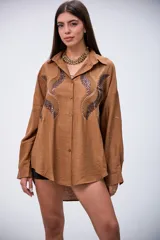 Camisa marrón de manga larga con detalles de lentejuelas y bordados en el frente. Tiene cuello clásico y botones frontales.