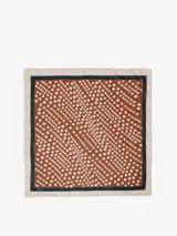 Pañuelo cuadrado confeccionado en una mezcla de algodón y seda. Presenta un diseño de lunares blancos sobre un fondo marrón, con un borde interior en contraste de color azul oscuro y un borde exterior en tono beige.