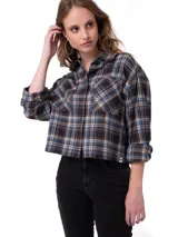 Camisa de corte cropped y diseño holgado, confeccionada en tela de franela con estampado a cuadros en tonos negro, azul y naranja. Presenta cuello camisero, cierre frontal con botones metálicos, mangas largas con puños abotonados y bolsillos frontales en el pecho.