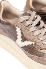 Championes de diseño deportivo en tonos marrón y cobre, con detalles metálicos, suela de goma en color tostado y el logotipo lateral en forma de V.