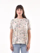 Remera manga corta de color beige con estampa botánica y floral en tonos verde, gris y salmón, de corte holgado.