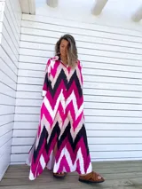 Vestido camisero largo con diseño de estampado chevron en colores fucsia, beige y negro. Presenta cuello camisero, cierre frontal con botones y mangas tres cuartos.