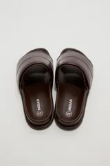Sandalias planas color marfil, con tira ancha acolchada en el empeine y suela baja con borde oscuro.