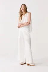 Conjunto de pantalón y top blancos de lino. El pantalón es de corte ancho con cintura elástica y bolsillos laterales. El top es sin mangas y de corte recto.