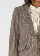 Blazer de corte clásico con solapas, cierre frontal de un botón y bolsillos laterales con solapa. Presenta una textura tejida con patrón de pequeños puntos en tonos neutros.