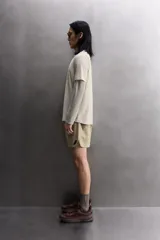 Camiseta de entrenamiento regular fit color beige, confeccionada en combinación de tejidos técnicos ligeros y elásticos con tecnología Quick Dry nivel 2. Presenta cuello redondo, manga corta, acabados con costuras planas y termofijadas, y detalle de logo estampado en el bajo.