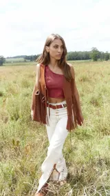 Pantalón de jean blanco con corte acampanado, cintura alta, detalles trenzados y aplicaciones de cuero en la parte inferior.