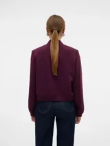 Campera tipo bomber color bordó, con cuello redondo, cierre frontal con botones a presión y bolsillos delanteros con solapa. Presenta puños y ruedo acanalados.