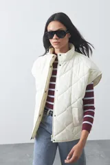 Chaleco acolchado de nylon con diseño capitoneado, cuello alto y cierre frontal con botones a presión. Presenta un calce amplio y versátil.