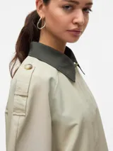 Campera corta de estilo parka con cuello camisero en contraste, cierre frontal con botones ocultos y bolsillos laterales. Presenta un diseño de corte recto con detalles en los hombros y mangas largas.