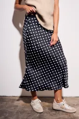 Falda midi de poliéster color negro con estampado de lunares blancos.