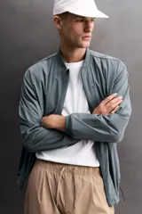 Chaqueta técnica de corte relajado, confeccionada en tejido compacto y elástico. Presenta cuello y puños acabados en rib, cierre frontal con cremallera, bolsillos frontales con cremallera oculta y bajo ajustable con elástico en los laterales.