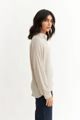 Blusa negra de manga larga con cuello tipo polo y escote en V. Presenta un diseño holgado con textura sutil en la tela y puños abotonados.