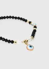 Pulsera elastizada con mostacillas blancas y doradas, con dije colgante de ojo turco con borde color cobre.