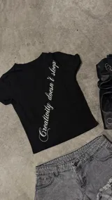 Remera negra de corte ajustado, con mangas cortas y estampa frontal diagonal con texto en color blanco.