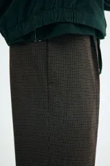 Pantalón de vestir marrón oscuro con microestampado a cuadros, corte relajado y pierna recta. Presenta pinzas frontales y bolsillos al bies.