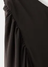 Vestido largo negro de corte entallado y diseño asimétrico, sin mangas, con detalle de capa en el cuello y fruncidos laterales.