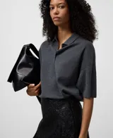 Falda midi negra de efecto piel, con textura arrugada en la parte superior y pliegues amplios en el resto de la falda.