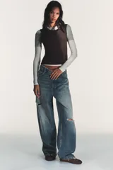 Camiseta de manga larga con diseño de capas superpuestas que crea un efecto triple. Presenta cuello redondo, corte ajustado y combinación de colores en tonos blanco, gris y negro.