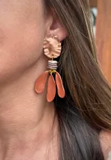 Caravanas colgantes con diseño artesanal, compuestas por una pieza superior de metal texturizado en tono cobre, una sección central de cuentas apiladas y tres pétalos colgantes en color cobre brillante.