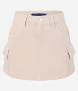 Pollera corta de sarga color beige claro, con cintura con trabillas y cierre de botón y cremallera. Presenta bolsillos cargo funcionales a los lados.