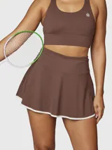 Falda skort deportiva color chocolate con short integrado, confeccionada en tejido técnico de secado rápido con borde inferior en contraste blanco.