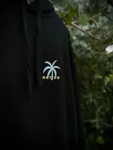 Hoodie negro de corte oversize con capucha y estampado gráfico en la espalda que incluye cuatro recuadros con motivos playeros y la palabra Coastline.