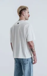 Remera de algodón premium color blanco tiza, con corte crop, calce oversize, hombros caídos y cuello redondo.