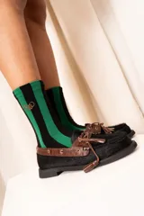 Medias de caña alta a rayas verticales negras y verdes, con detalle de logo bordado en el lateral.